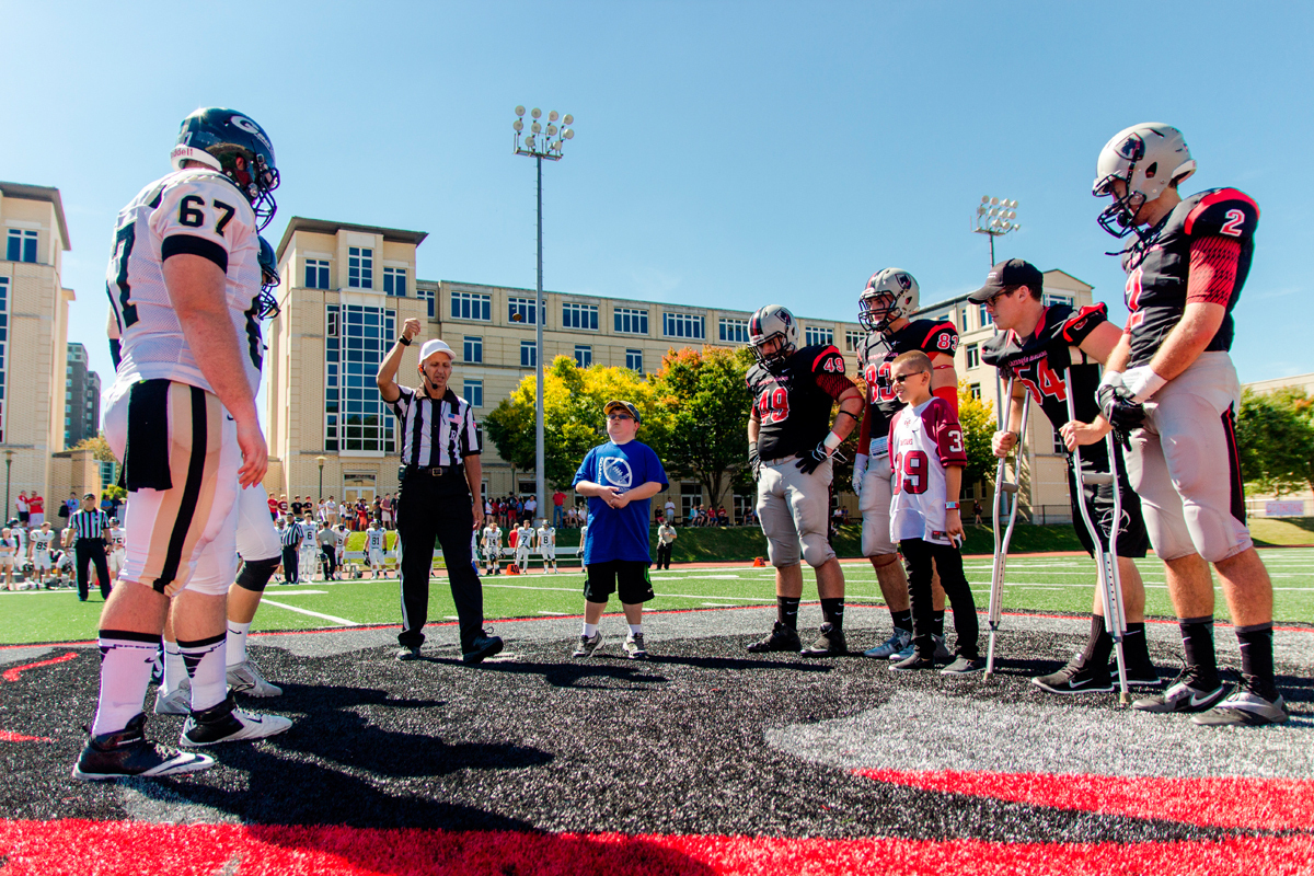 The Tartans, accompanied by their smallest new member, Brock Kitterman, face off in the coin toss against the Geneva Golden Tornadoes in the first home game in which Team IMPACT participated. (credit: Kevin Zheng/)